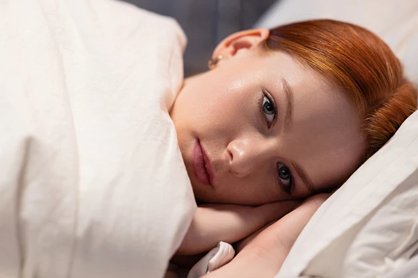 Woman laying on a bed with a blanket
